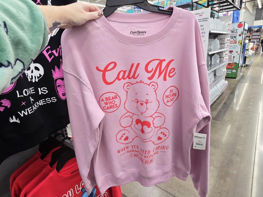 hand holding up a pink and red care bears sweatshirt