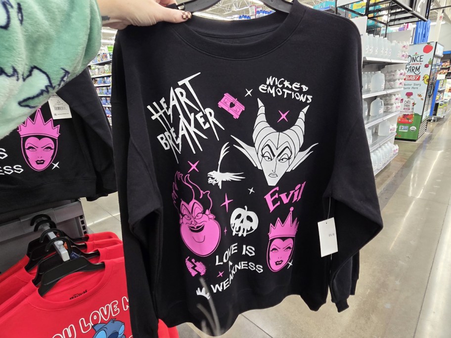 hand holding up a black and pink disney villains sweatshirt