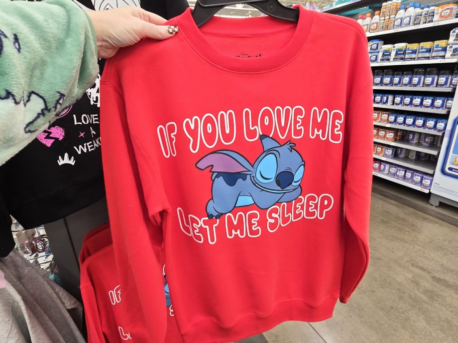 woman holding up a red stitch sweatshirt that says if you love me let me sleep