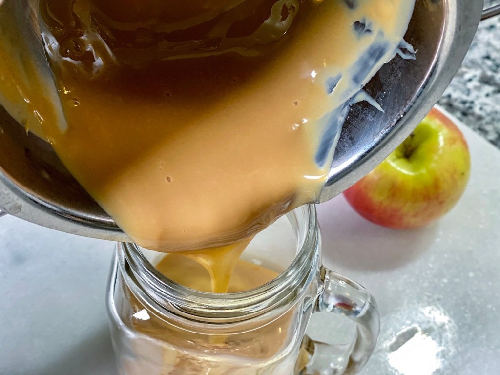 homemade caramel sauce being poured into mason jar