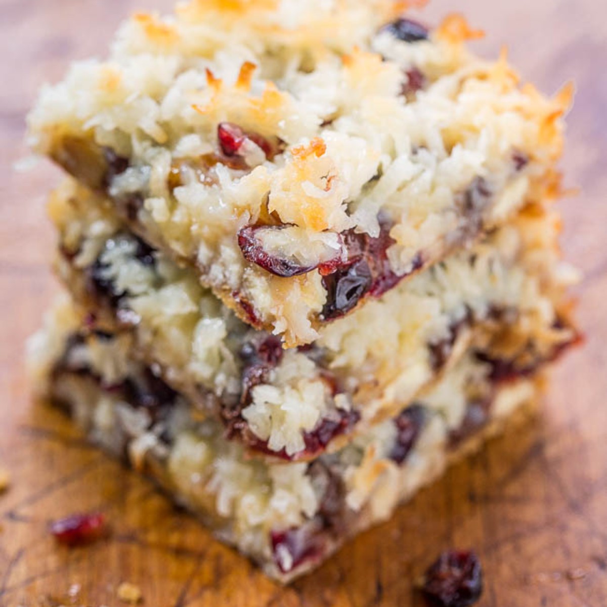 3 cranberry cookie bars stacked on cutting board