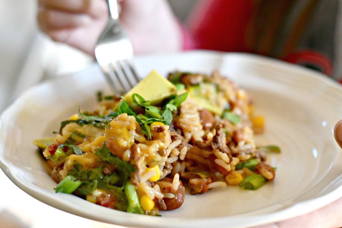 taco rice beans skillet casserole &ndash; a fork going into a plate of the casserole