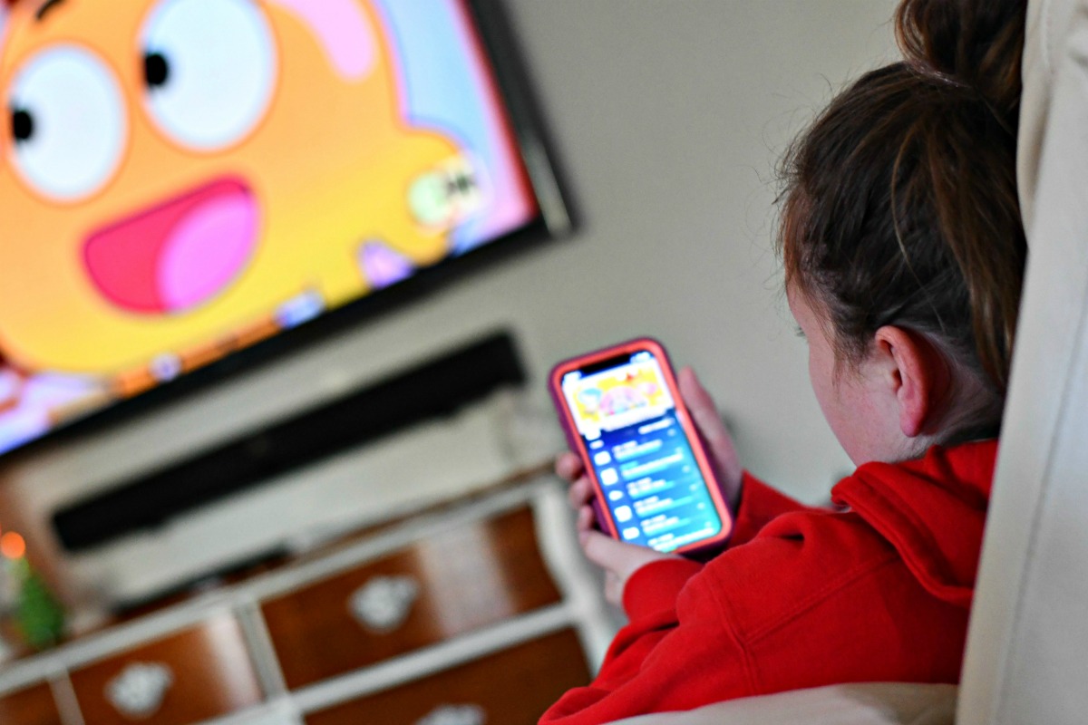 I saved 1200 on cable by streaming &ndash; child looking at a mobile device while watching tv