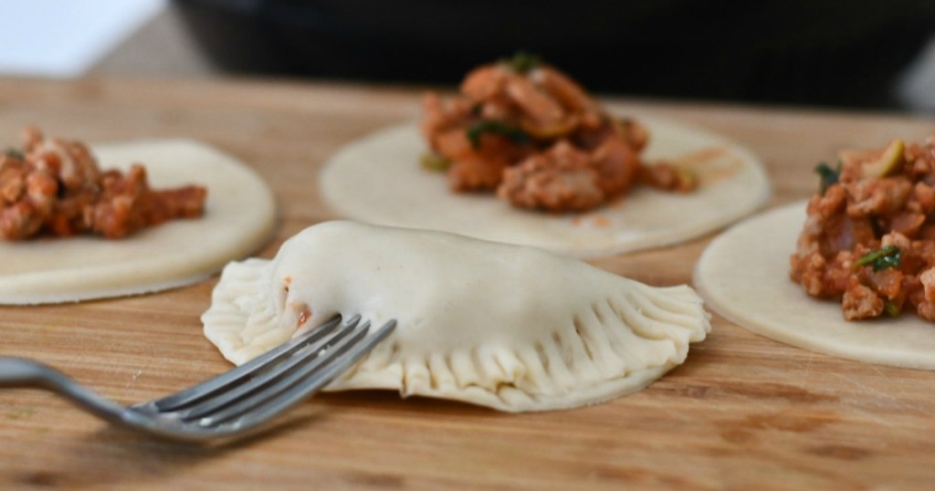 pressing the fork into the edges of the empanadas