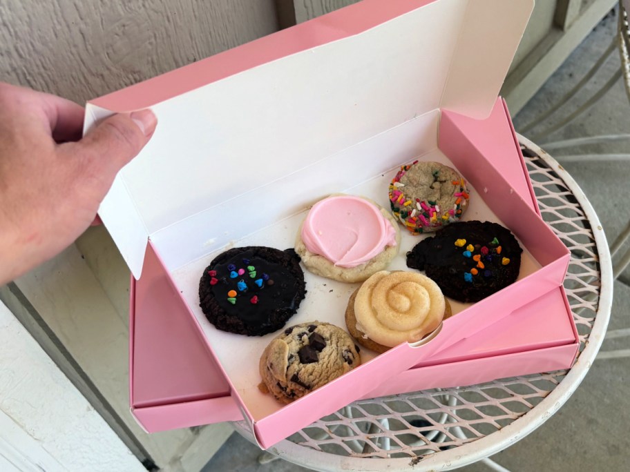 Person opening six pack box of crumbl mini cookies