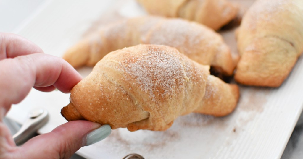 holding a nutella crescent after baking with cinnamon and sugar