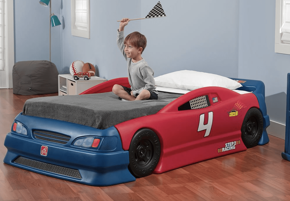 Toddler boy sitting on Step2 Stock Car Convertible Bed