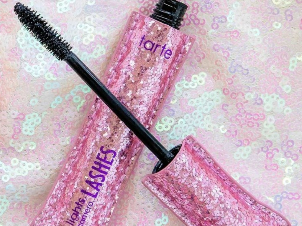 pink bottle of mascara sitting amoung glitter