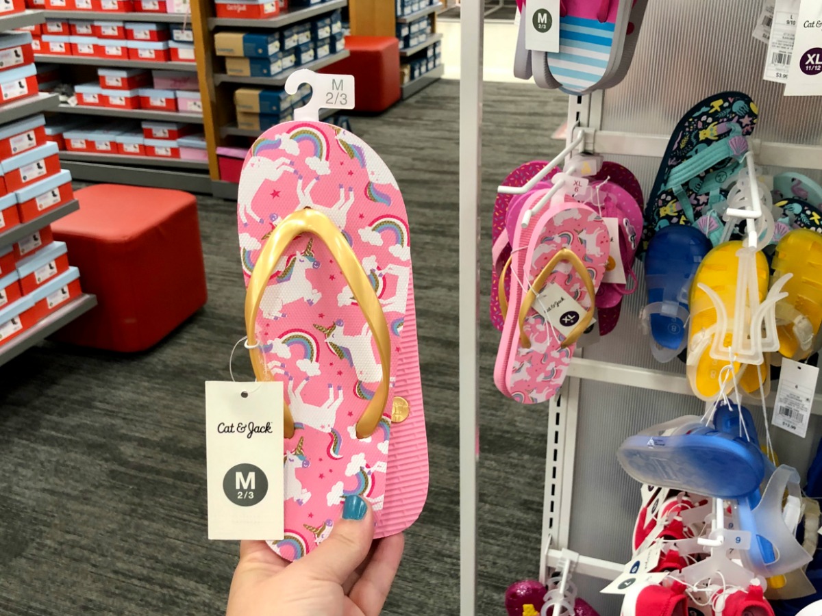 hand holding unicorn flip flops in target
