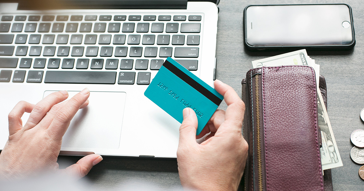 person at computer with credit card using their rewards because its the cheapest way to rent a car