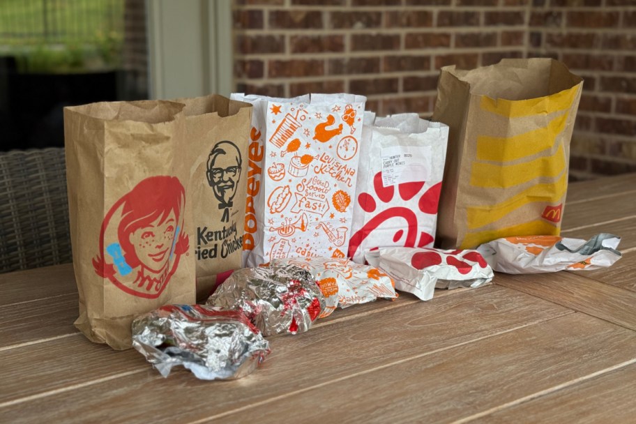 mcdonalds, wendys, KFC, popeyes, and chick fil a meal bags in a line