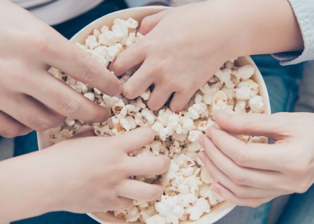 hands in popcorn bowl