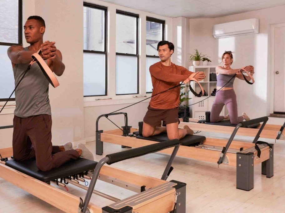 3 people working out on pilates reformers
