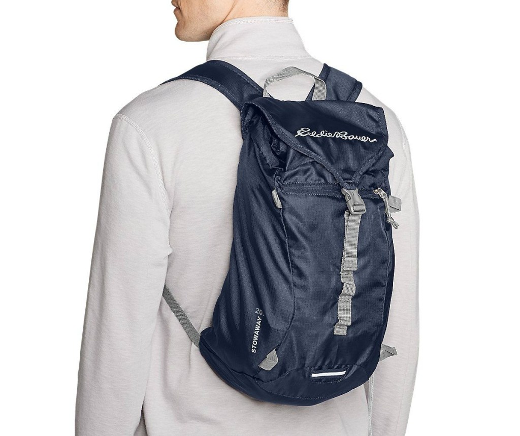 man wearing navy Eddie Bauer Stowaway Packable 20L Ruck Pack 