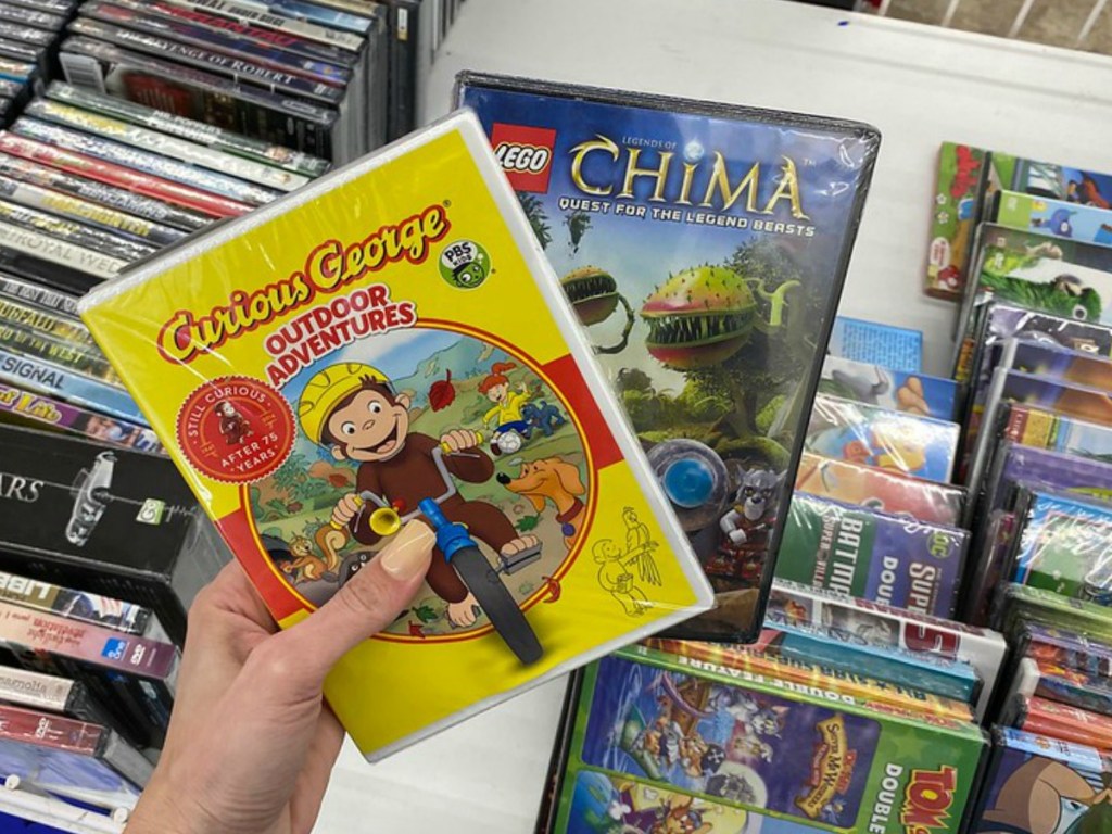 hand holding two DVDs with kids titles in store