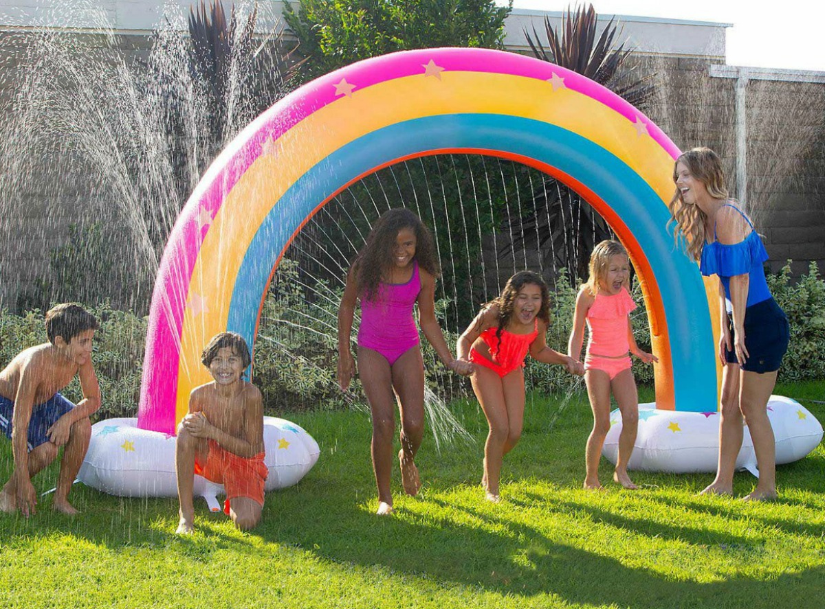kids playing around a giant rainbow sprinkler