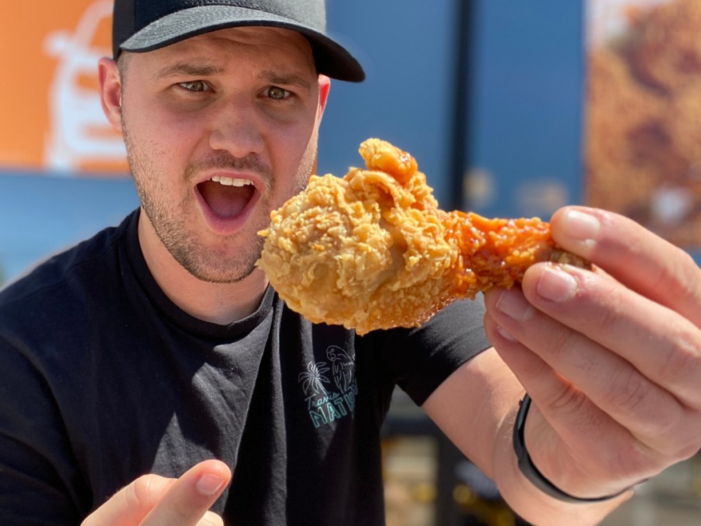 man holding up chicken leg