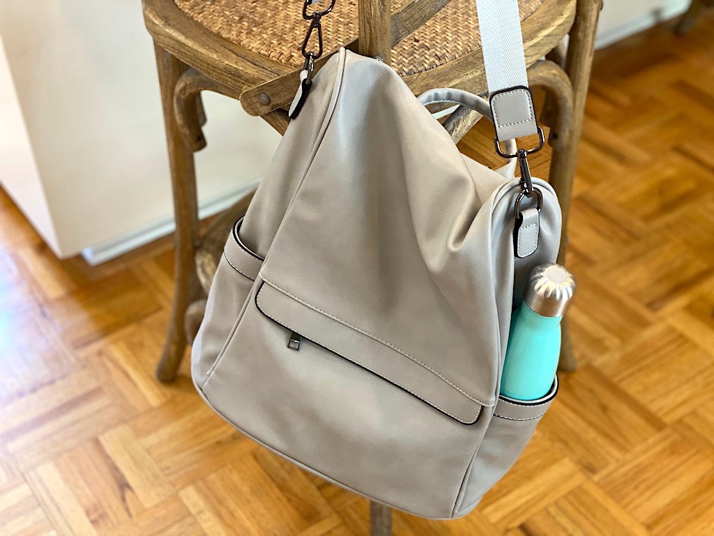 grey purse with water bottle handing from stool 