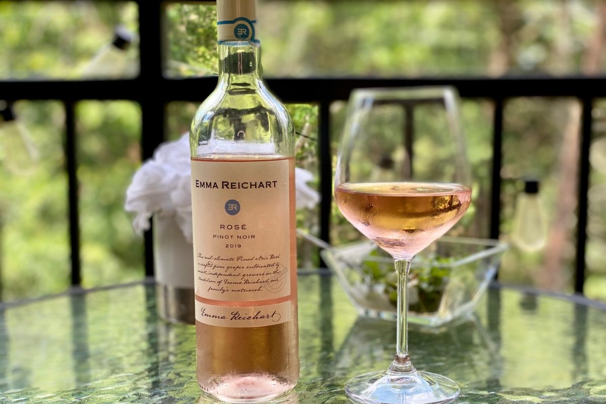 A bottle of ros&eacute; next to a wine glass on a table