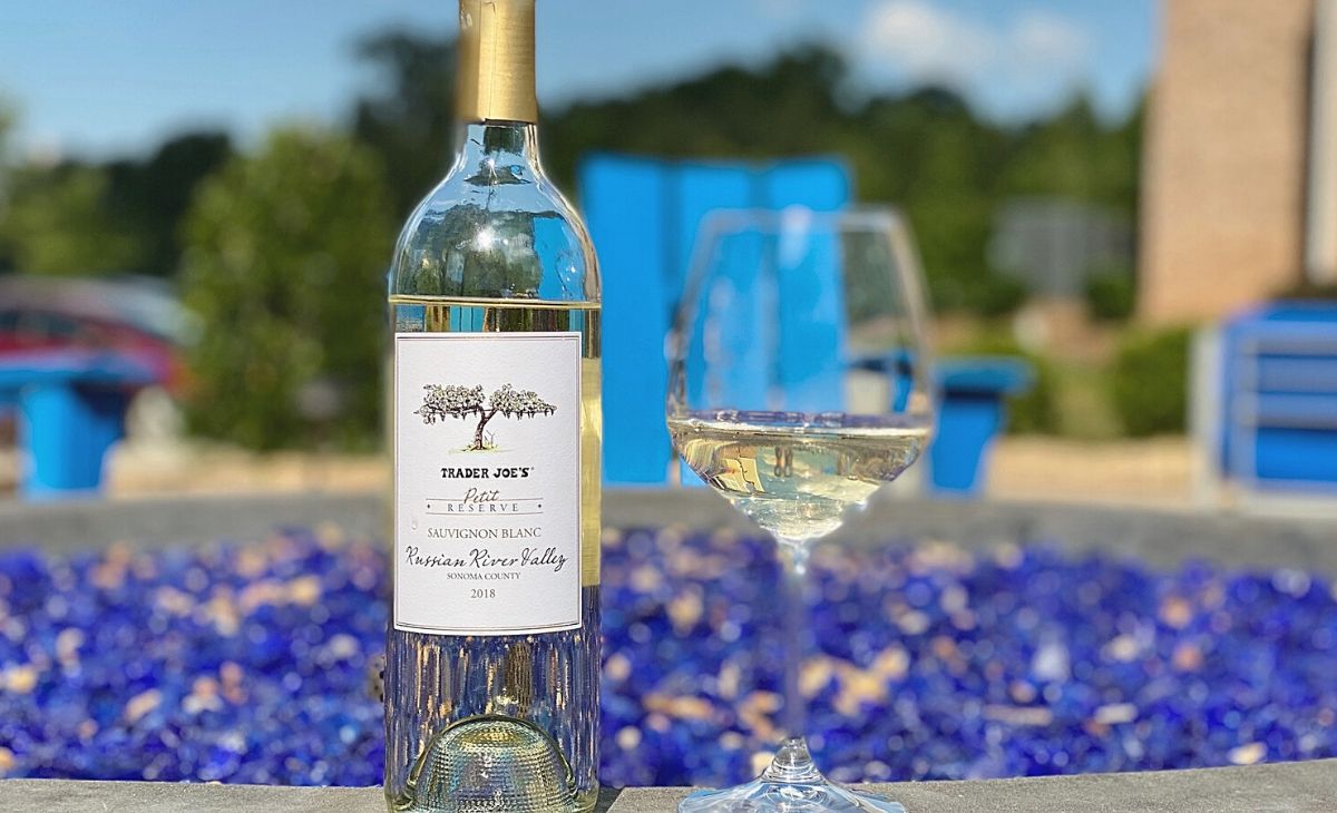 A bottle of wine and a wine glass next to a fire pit outside