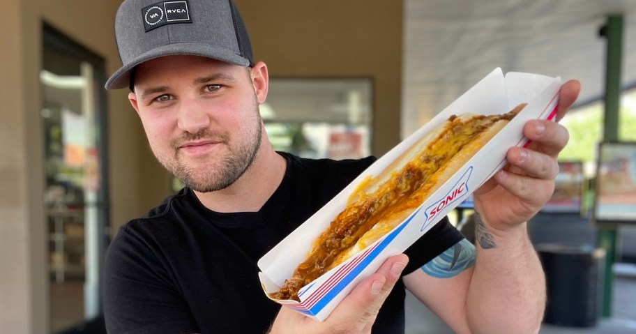 man holding Sonic Footlong Coney Chili cheese wearing black shirt and grey hat