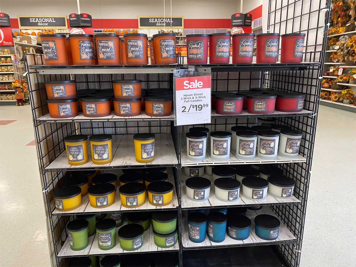 store display of glass jar candles with a sale sign