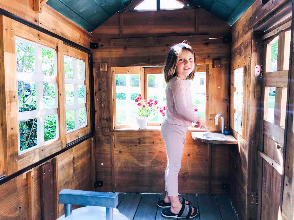 girl standing inside of kids playhouse