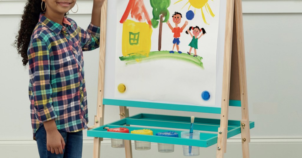 girl using white and blue wooden floor easel