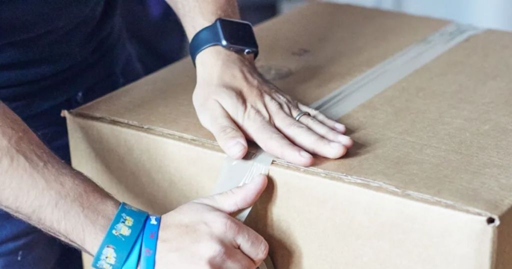 man sealing box with Staples Bulk Shipping Tape