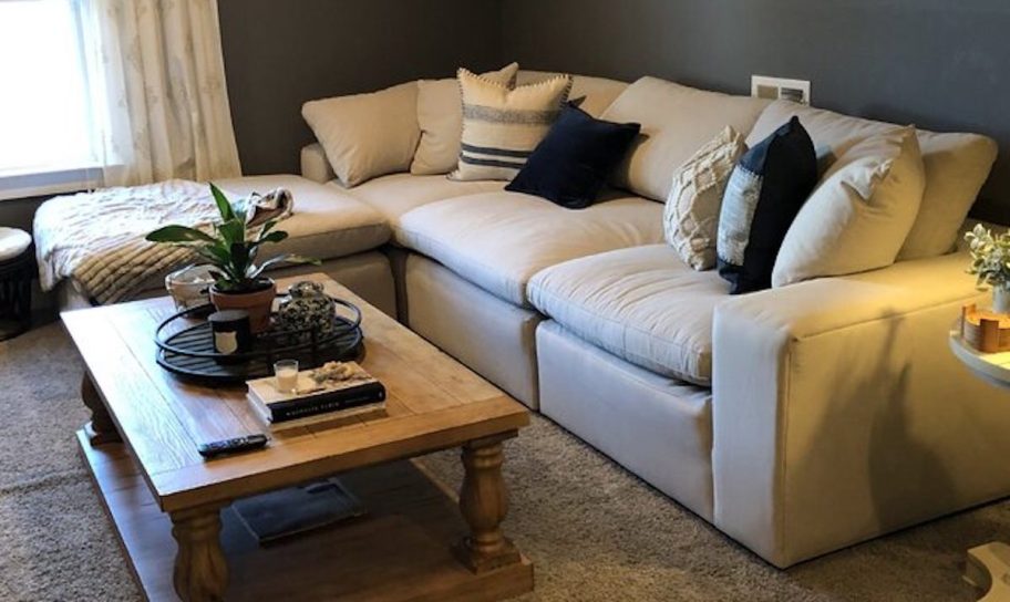 tan sectional sitting in styled living room with wood coffee table