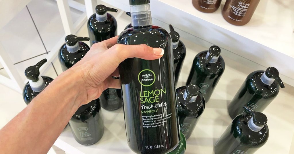 person holding up large green bottle of tea tree shampoo
