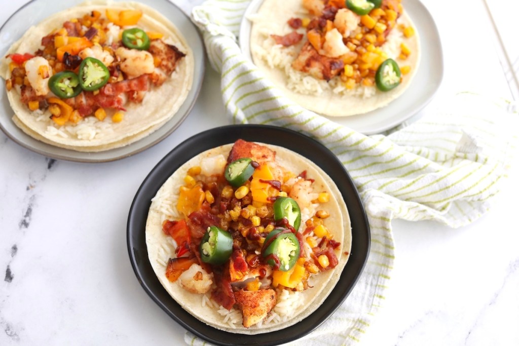 tacos with food on tortillas sitting on plates on countertop