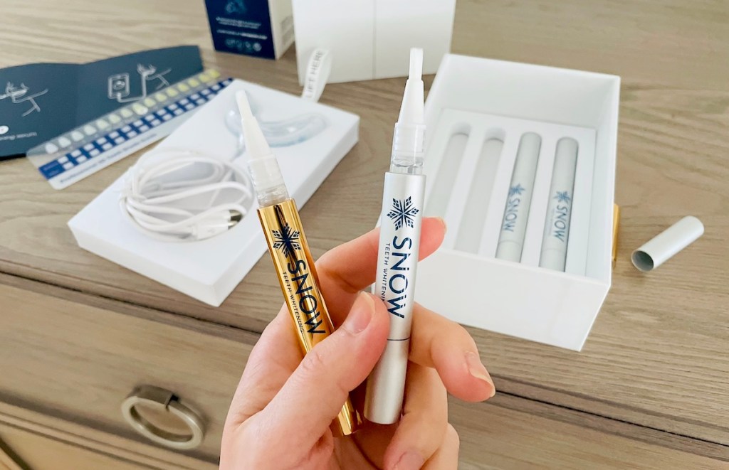 hand holding two tubes of whitening gel
