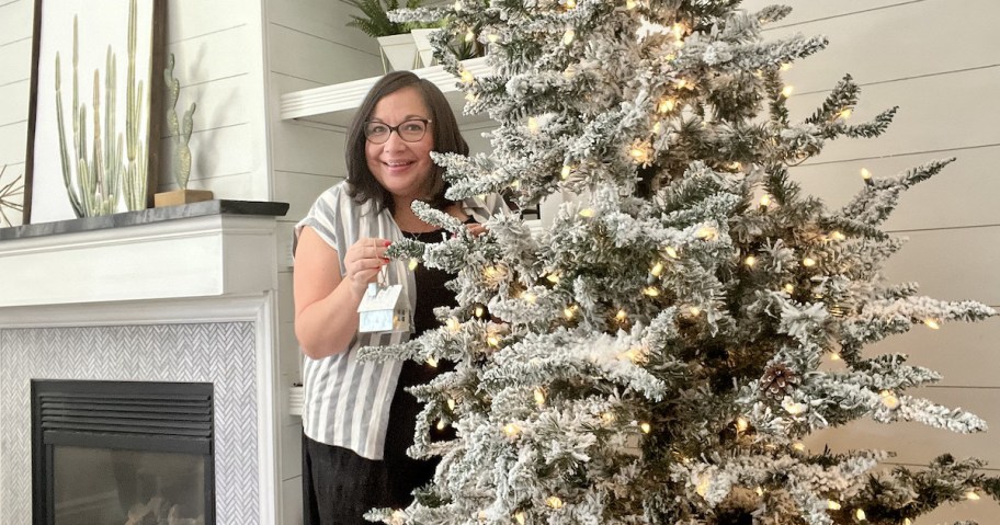 woman standing next to pre lit flocked christmas tree