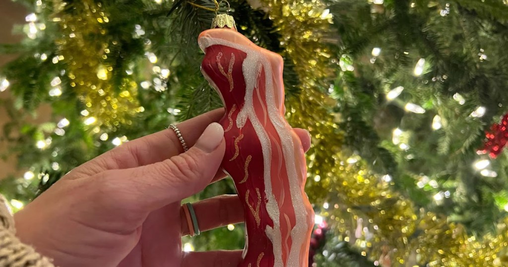holding bacon ornament hanging on Christmas tree 