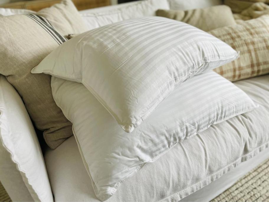 two linens and hutch pillows stacked on couch
