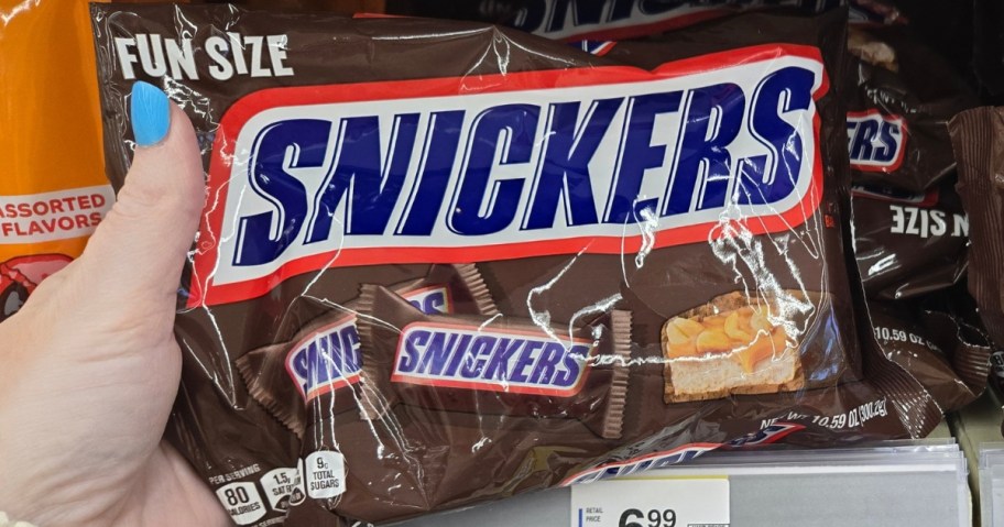 hand holding a bag of Snickers fun size candy bars