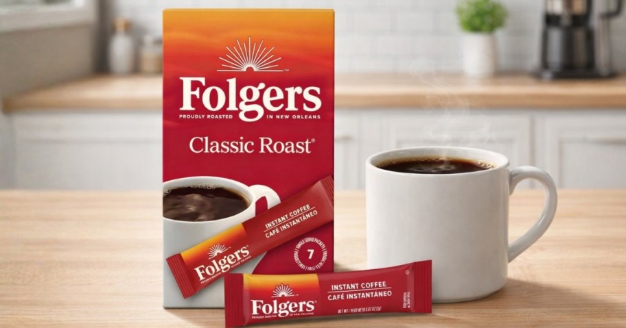 a box of Folger's Instant Coffee packets, a packet, and a coffee mug on a counter