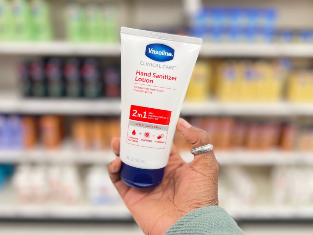 hand holding bottle of hand sanitizer body lotion in store