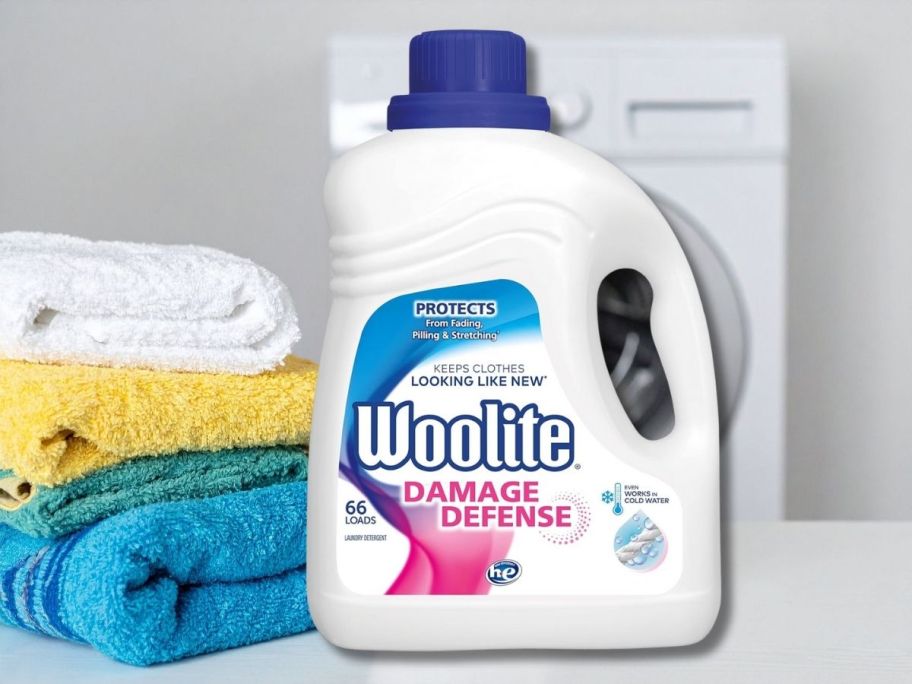 Woolite Laundry Detergent in front of a washing machine and beside towels