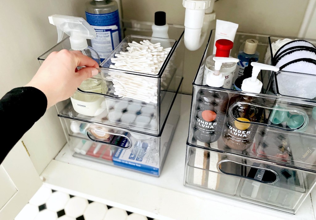 hand holding organized clear container under bathroom sink the home edit products
