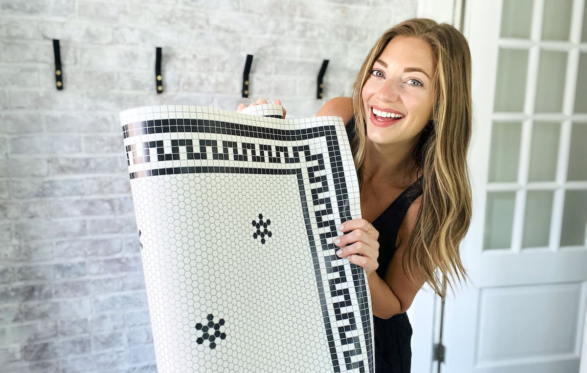 woman holding vinyl floor mat with tile pattern