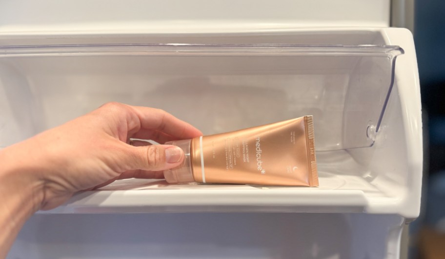 hand putting skincare mask tube in fridge