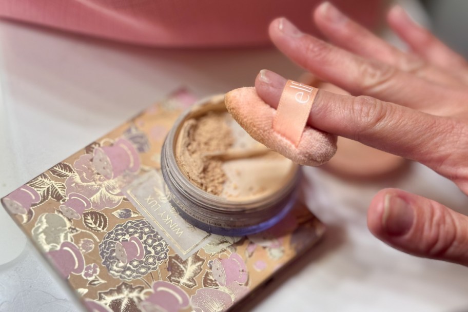 hand with makeup pom over powder