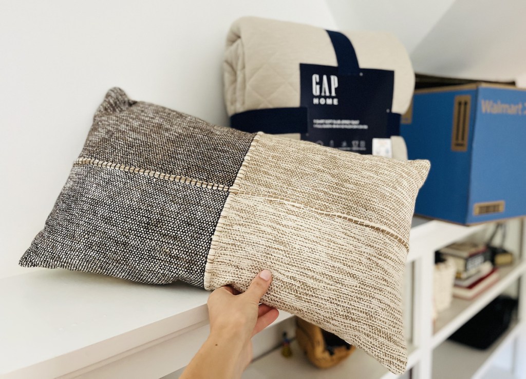 hand holding lumbar beige and brown pillow