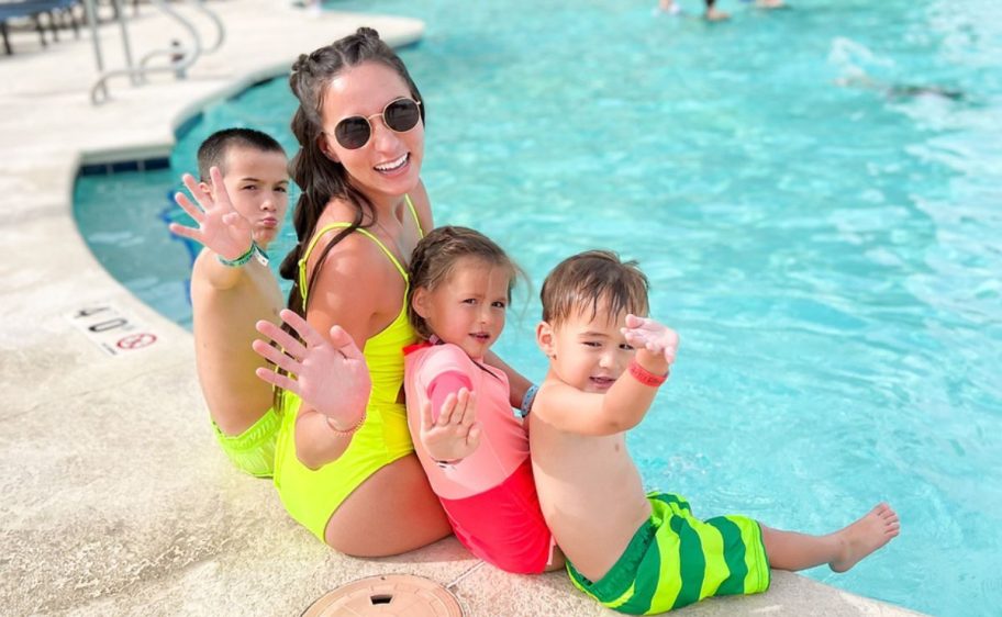 family sitting together on the side of a pool