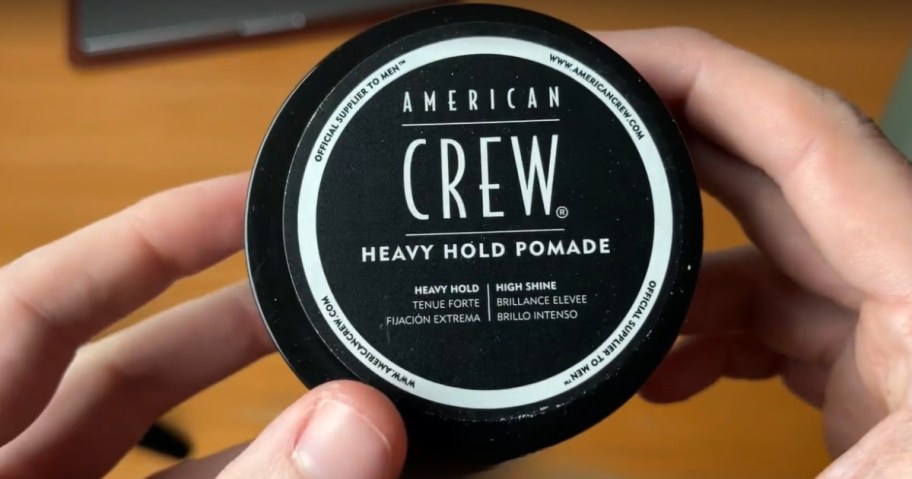 hand holding a container of American Crew hair pomade