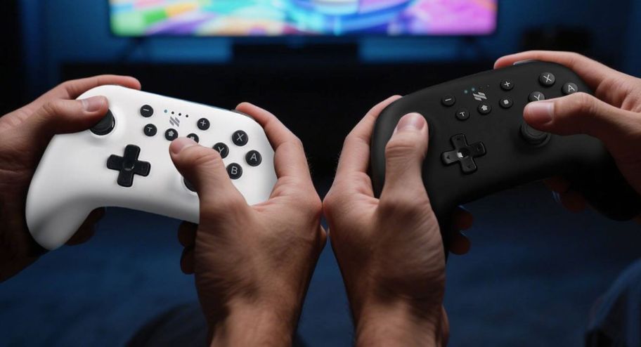 hand holding white and black controllers 