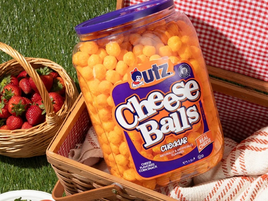 barrel of utz cheese balls in picnic basket with strawberries and picnic blanket