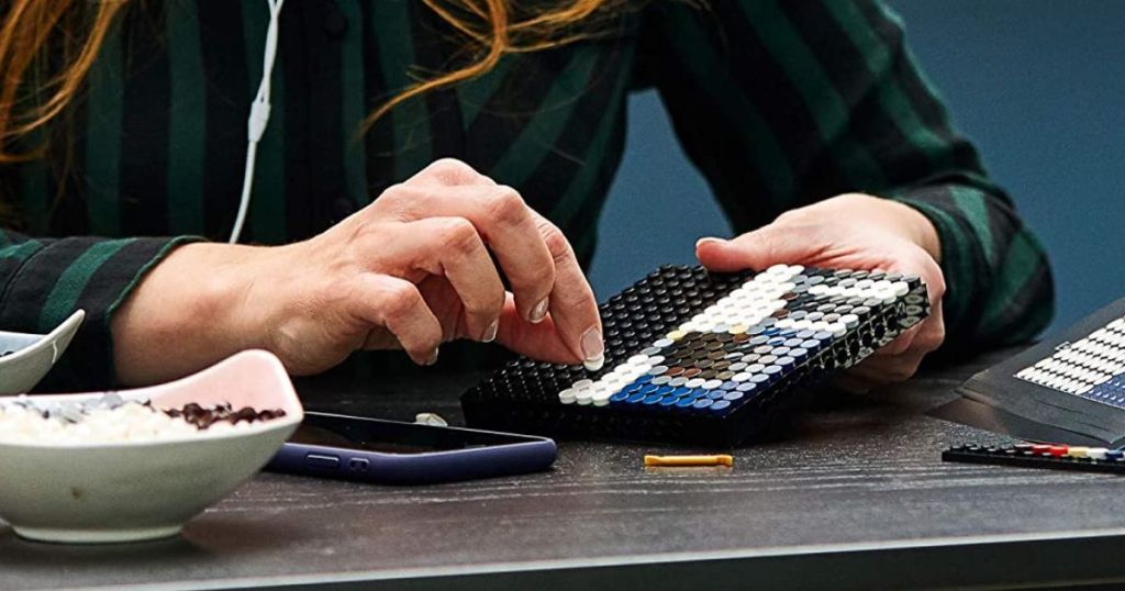 LEGO Art disney mickey mouse being assembled by a woman sitting at a table